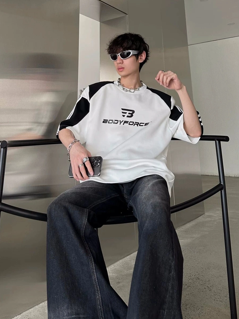 Relaxed varsity colorblock tee with chest graphic styled with dark denim in an industrial setting