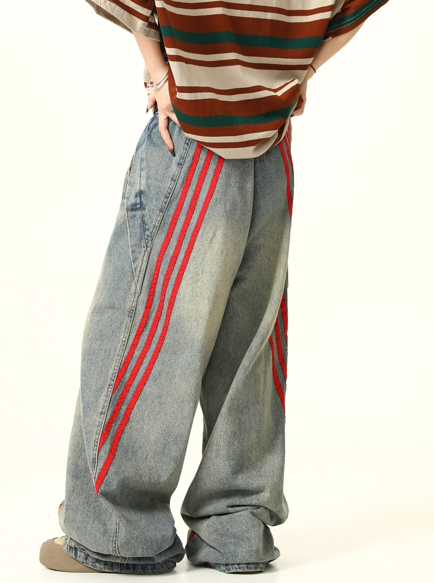 Side back view of relaxed wide-leg washed denim jeans with diagonal red triple-stripe details and worn-in streetwear texture