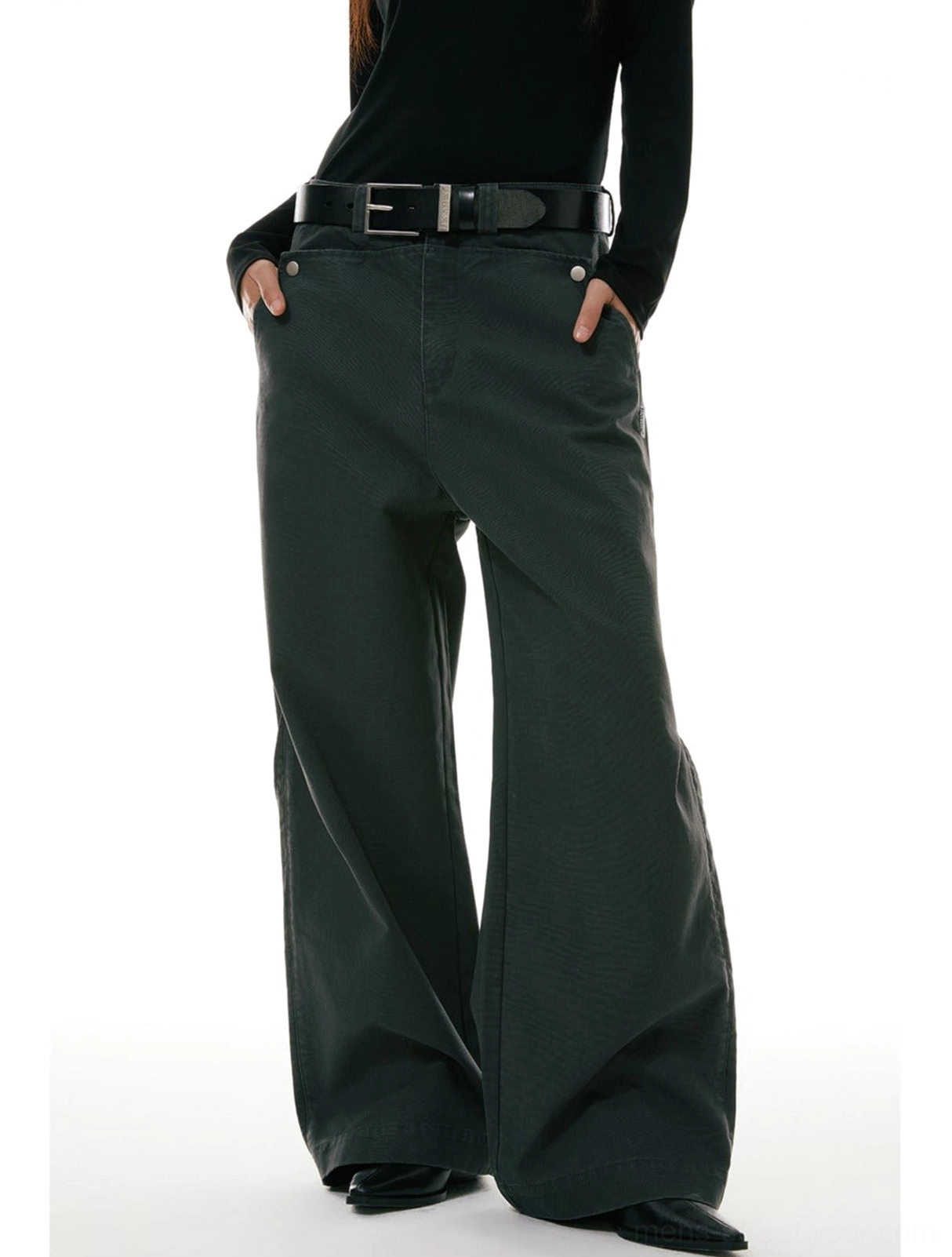 Low-angle front view of relaxed wide-leg workwear denim jeans styled with a high waist and front pockets in a minimalist white studio