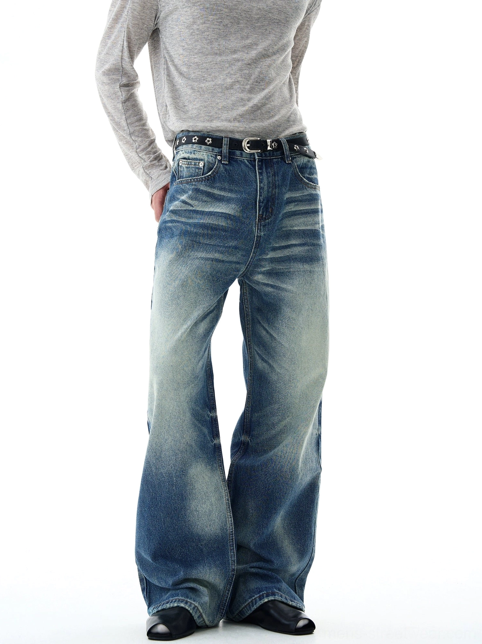 Three-quarter rear view of retro blue flare-leg jeans with visible front pocket, subtle inner-thigh fading, wide legs, and hem resting neatly over black shoes