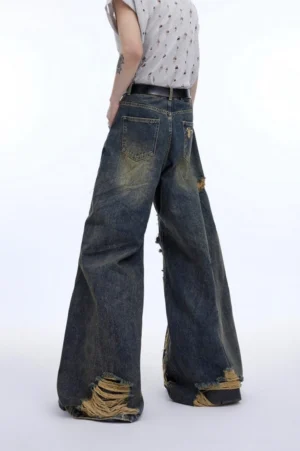 Back view of vintage washed blue deconstructed wide leg jeans showing relaxed oversized fit, rear pocket and frayed distressed hems