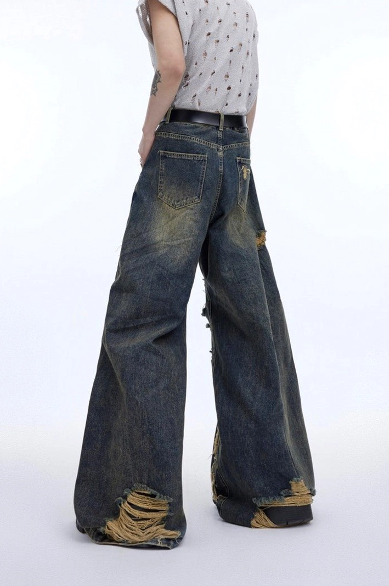 Back view of vintage washed blue deconstructed wide leg jeans showing relaxed oversized fit, rear pocket and frayed distressed hems