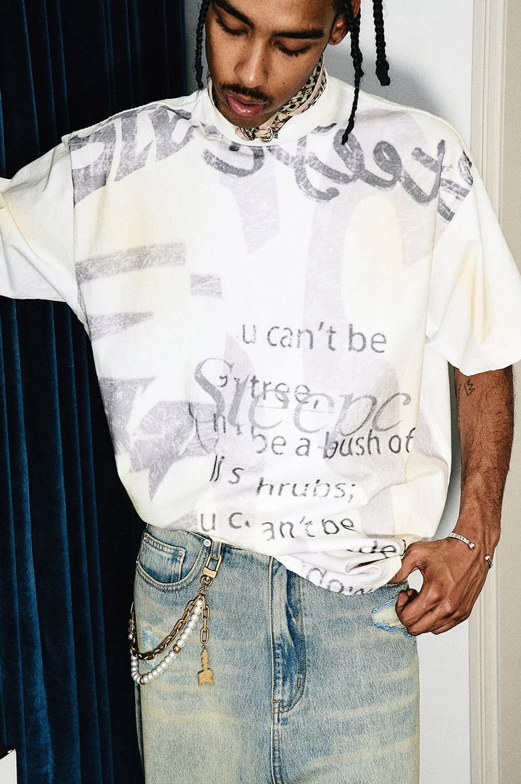 Close-up front view showing the retro gray graffiti text print and yellowed vintage texture of an oversized streetwear T-shirt