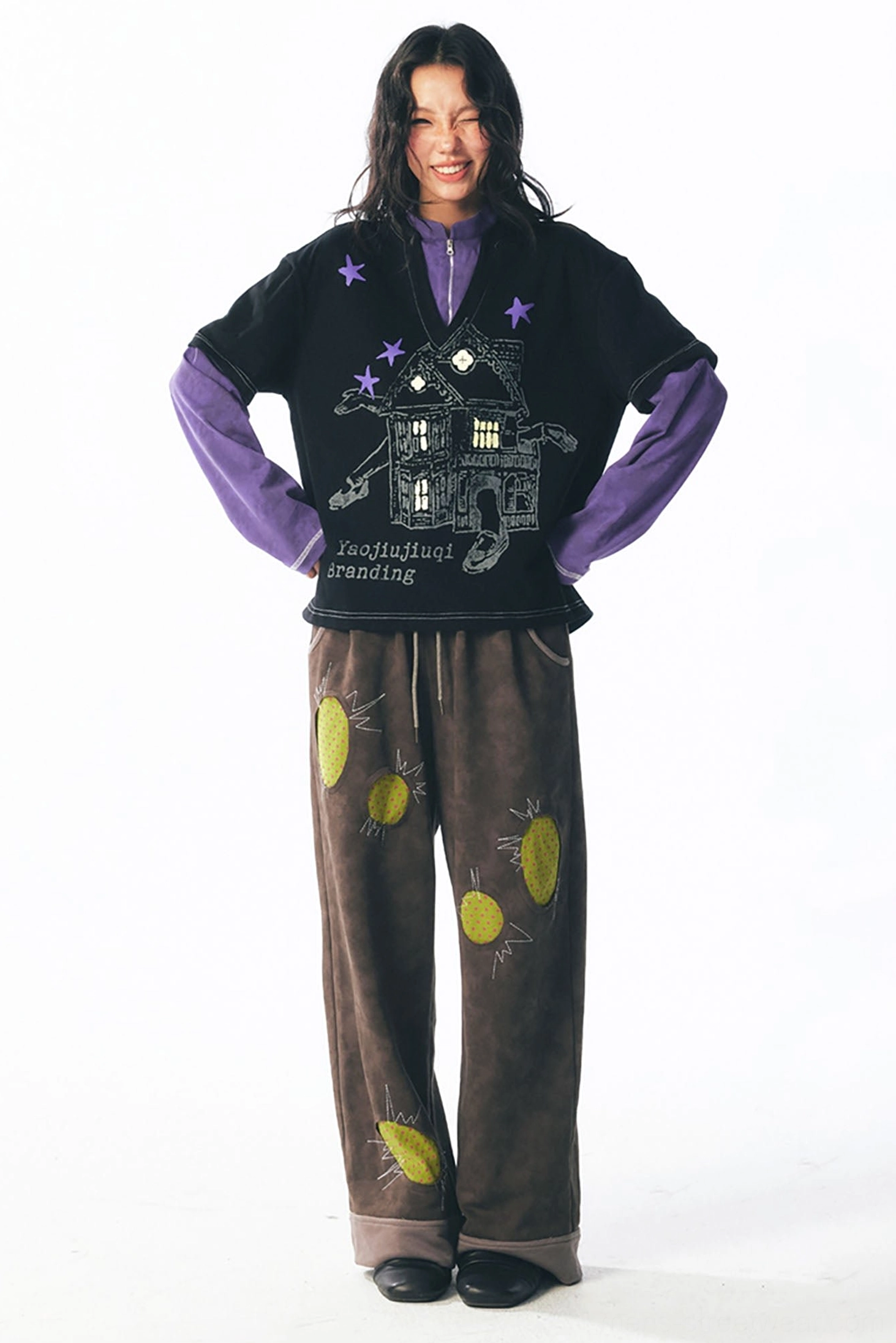 Front view of a relaxed layered graphic long sleeve tee featuring haunted house artwork and purple star accents