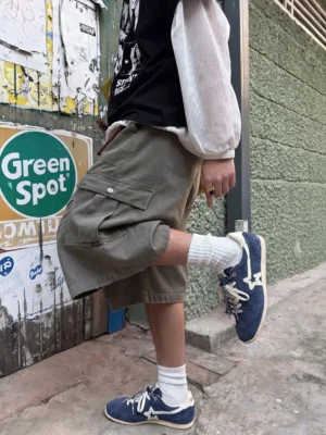 Navy blue retro suede trainers worn with olive cargo shorts and white crew socks in a Korean streetwear outfit
