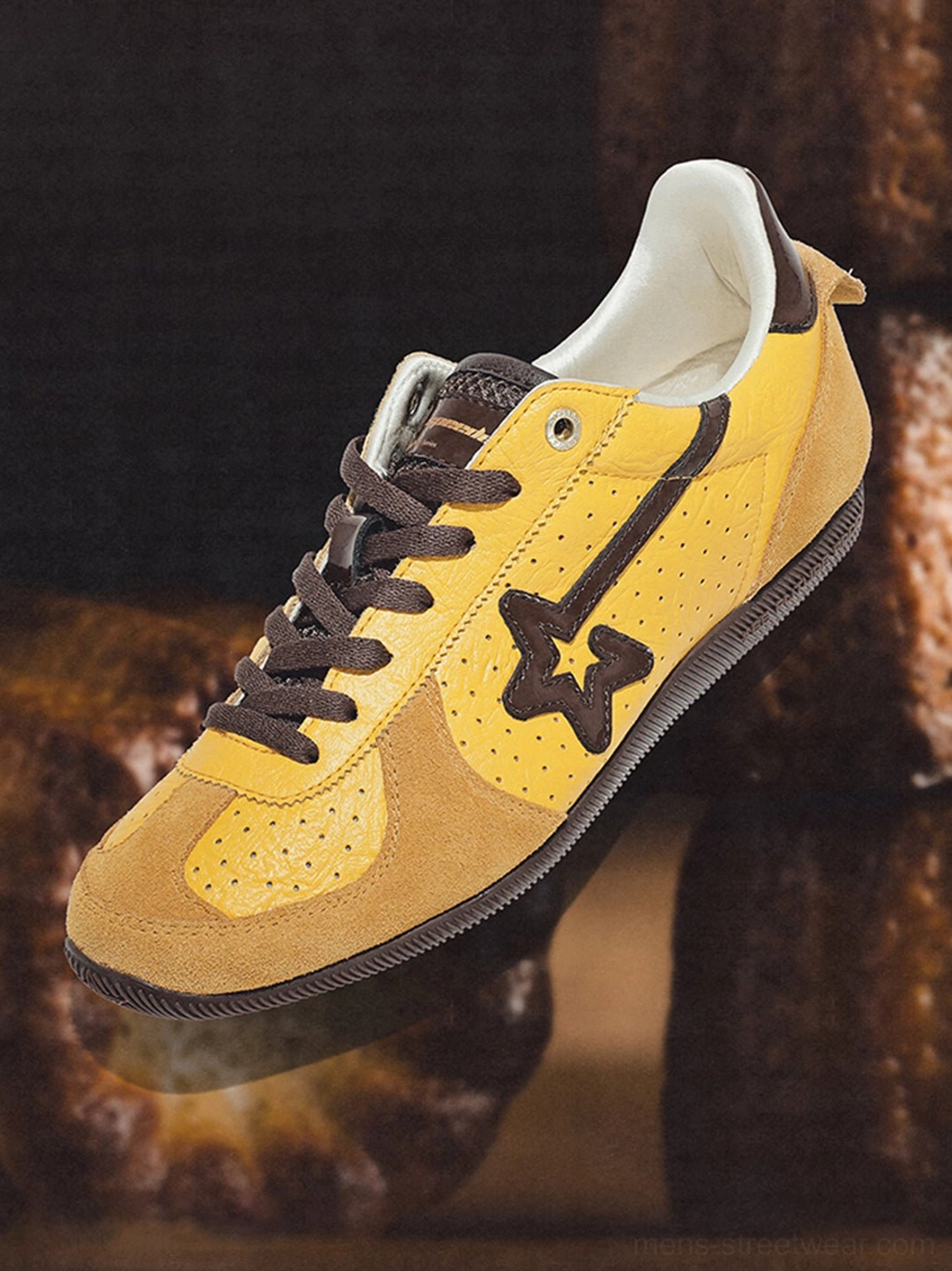 Yellow brown suede low-profile trainer close-up showing perforated upper, white lining, contrast panels, and rubber outsole