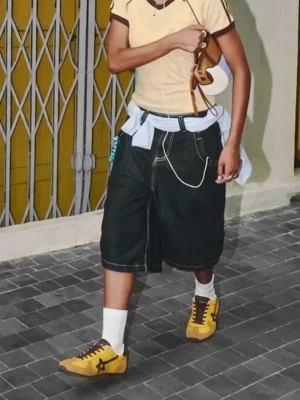 Yellow brown retro suede streetwear trainers styled with cropped tee, baggy shorts, and white crew socks on an urban street