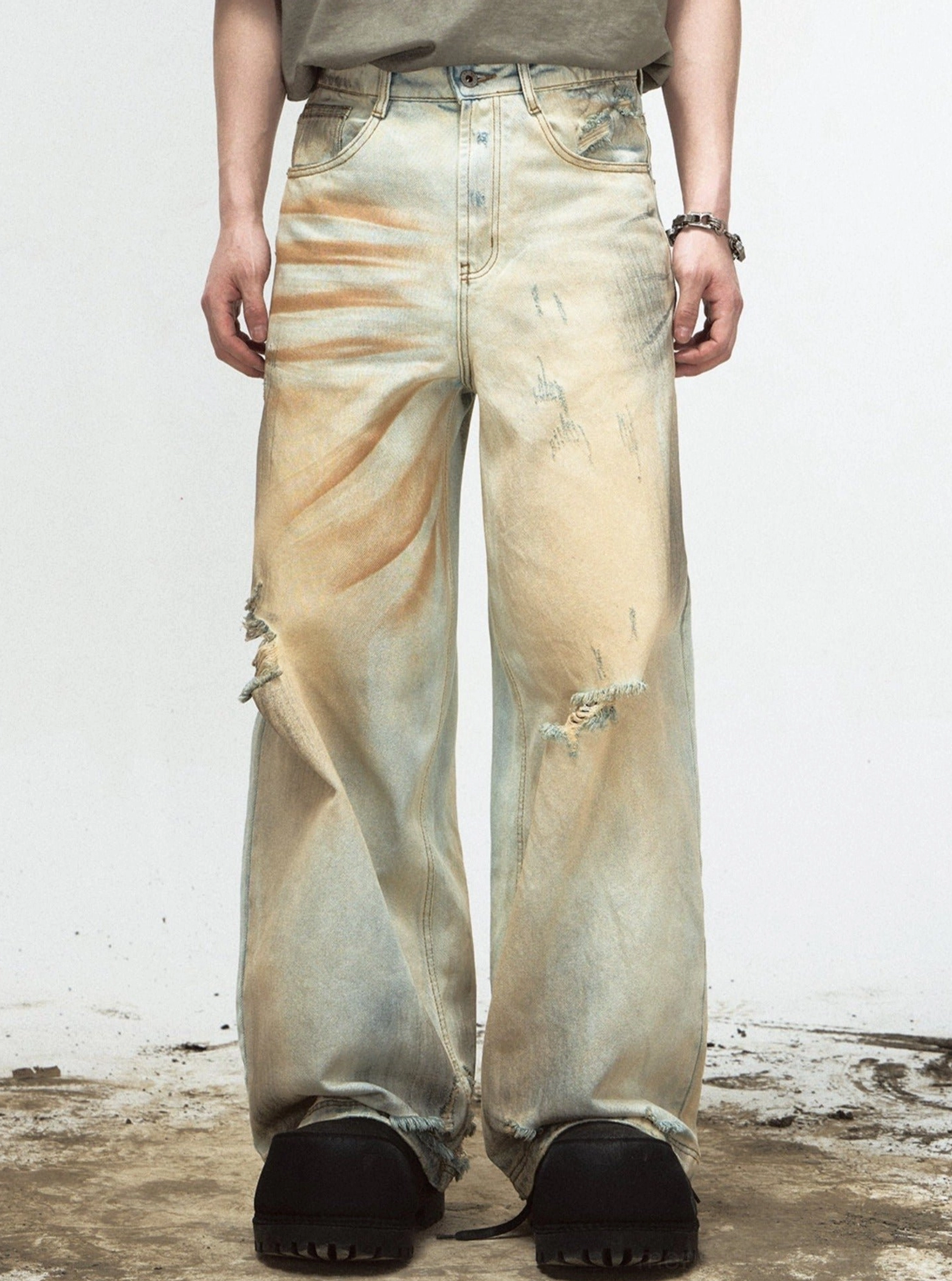 Front view of retro sun-faded yellow ripped wide-leg denim jeans on male model in a studio