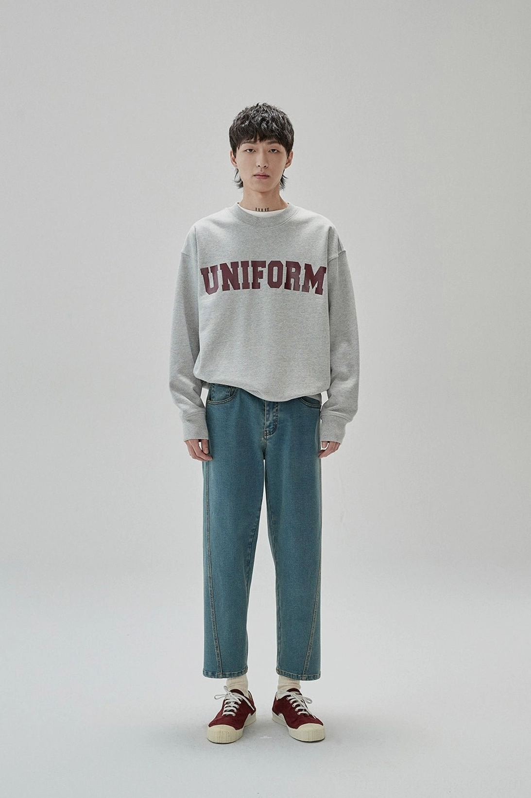 Full-body view of retro UNIFORM crewneck sweatshirt styled with blue jeans and burgundy sneakers