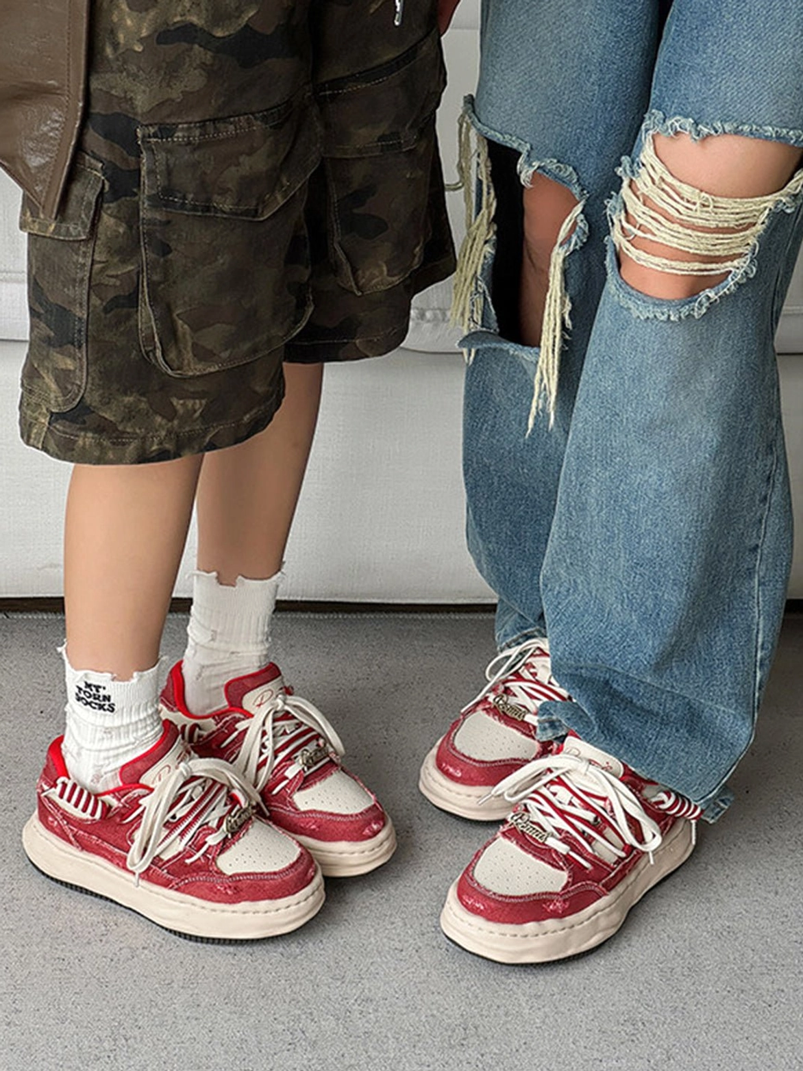 Two streetwear models wearing retro washed denim sneakers with camouflage shorts and ripped denim jeans to show versatile styling