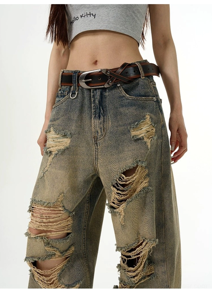 Close-up of waist and thigh on retro washed distressed wide-leg jeans showing belt loops and oversized frayed rips