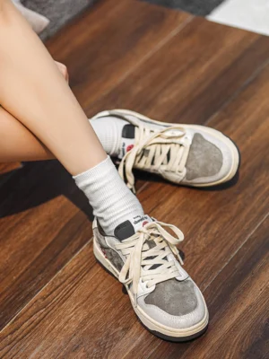 Retro worn-in suede leather sneakers styled with white crew socks on an indoor wooden floor