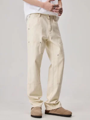 Men's off-white straight leg carpenter pants with utility side pocket and metal rivet details three quarter front view