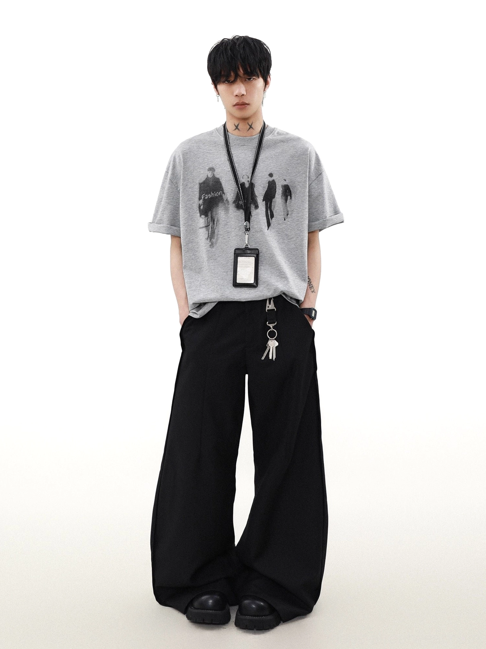 Heather gray oversized runway graphic T-shirt with loose silhouette, black wide-leg pants, and lanyard accessory