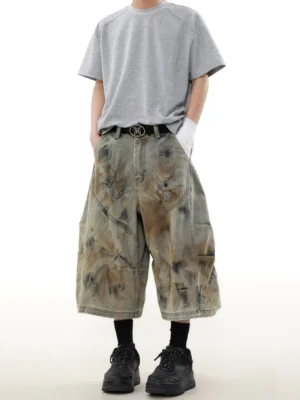 Front view of rust storm dyed wide-leg cargo denim shorts styled with a grey T-shirt black socks and chunky work boots