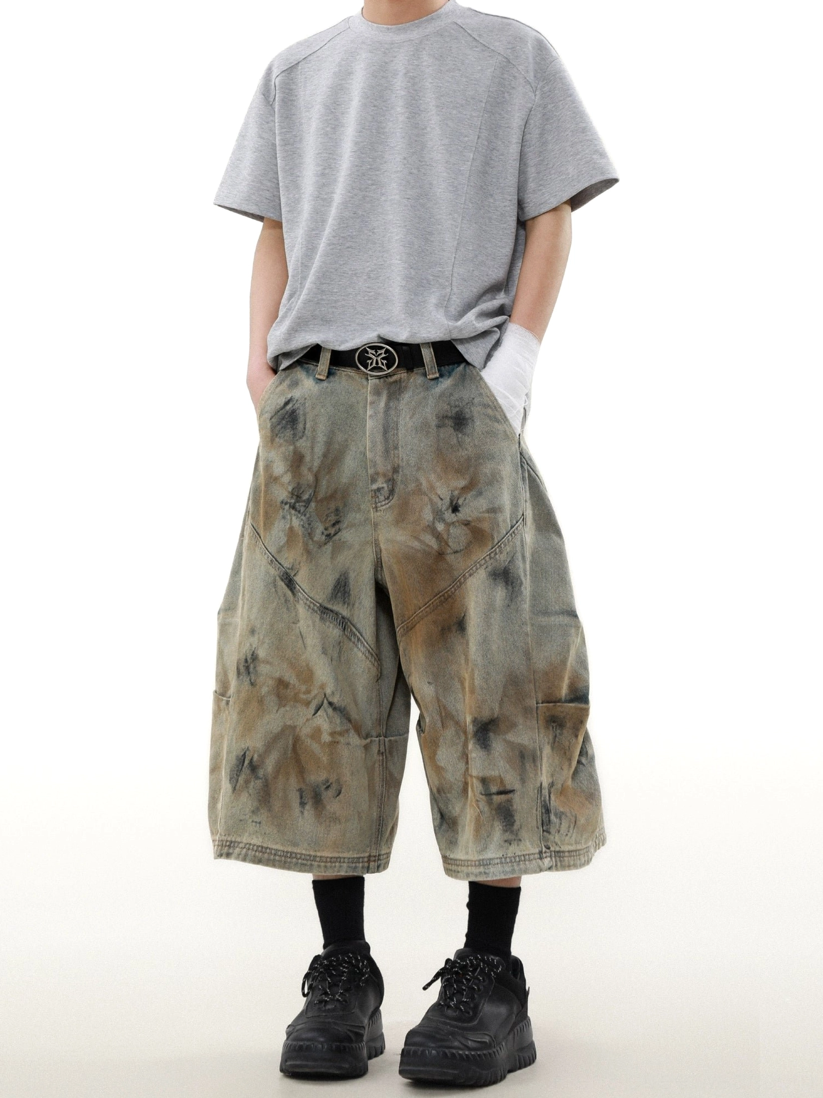 Front view of rust storm dyed wide-leg cargo denim shorts styled with a grey T-shirt black socks and chunky work boots