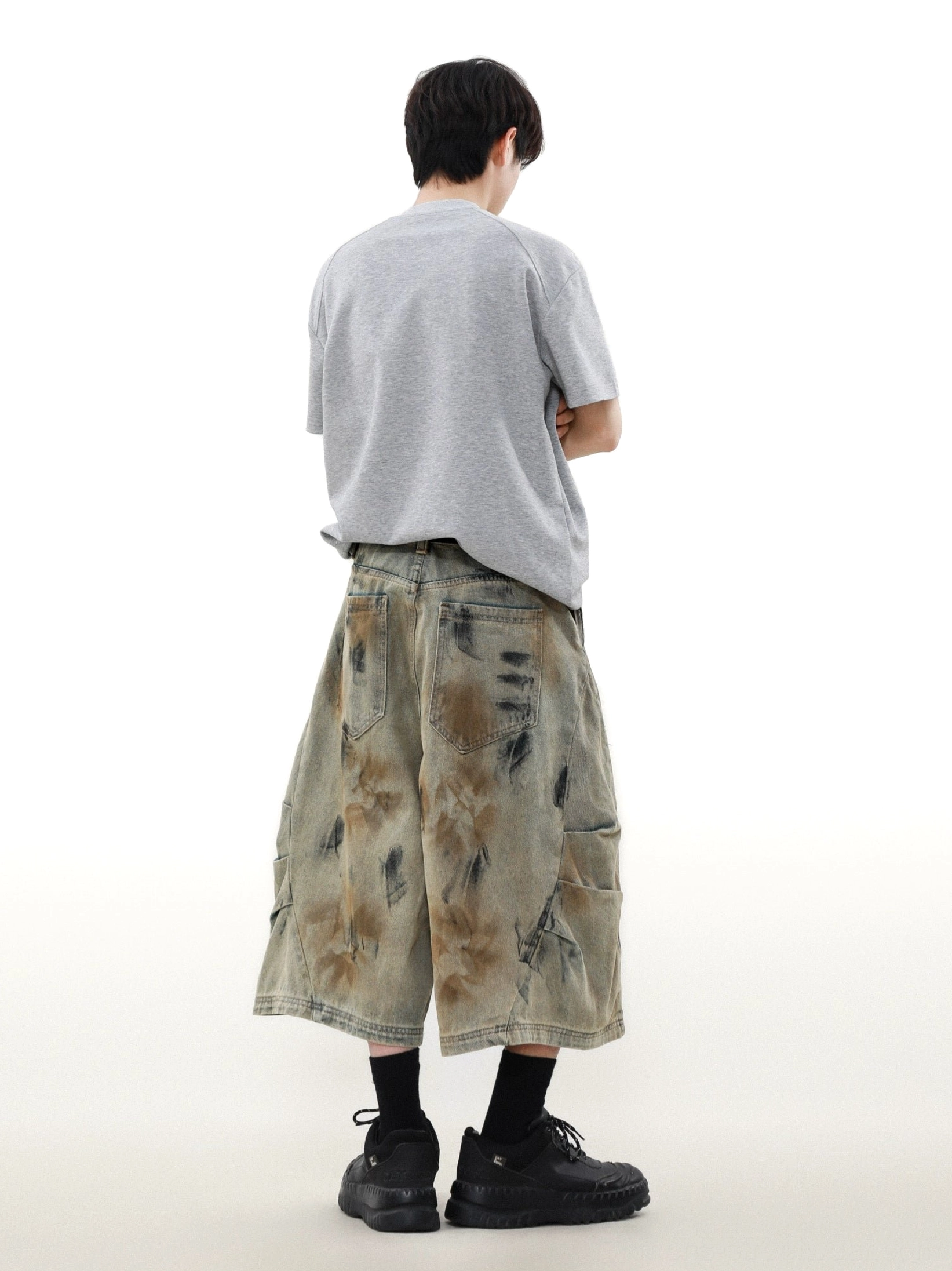 Rear view of wide-leg storm dyed denim cargo shorts with back patch pockets and vintage workwear finish