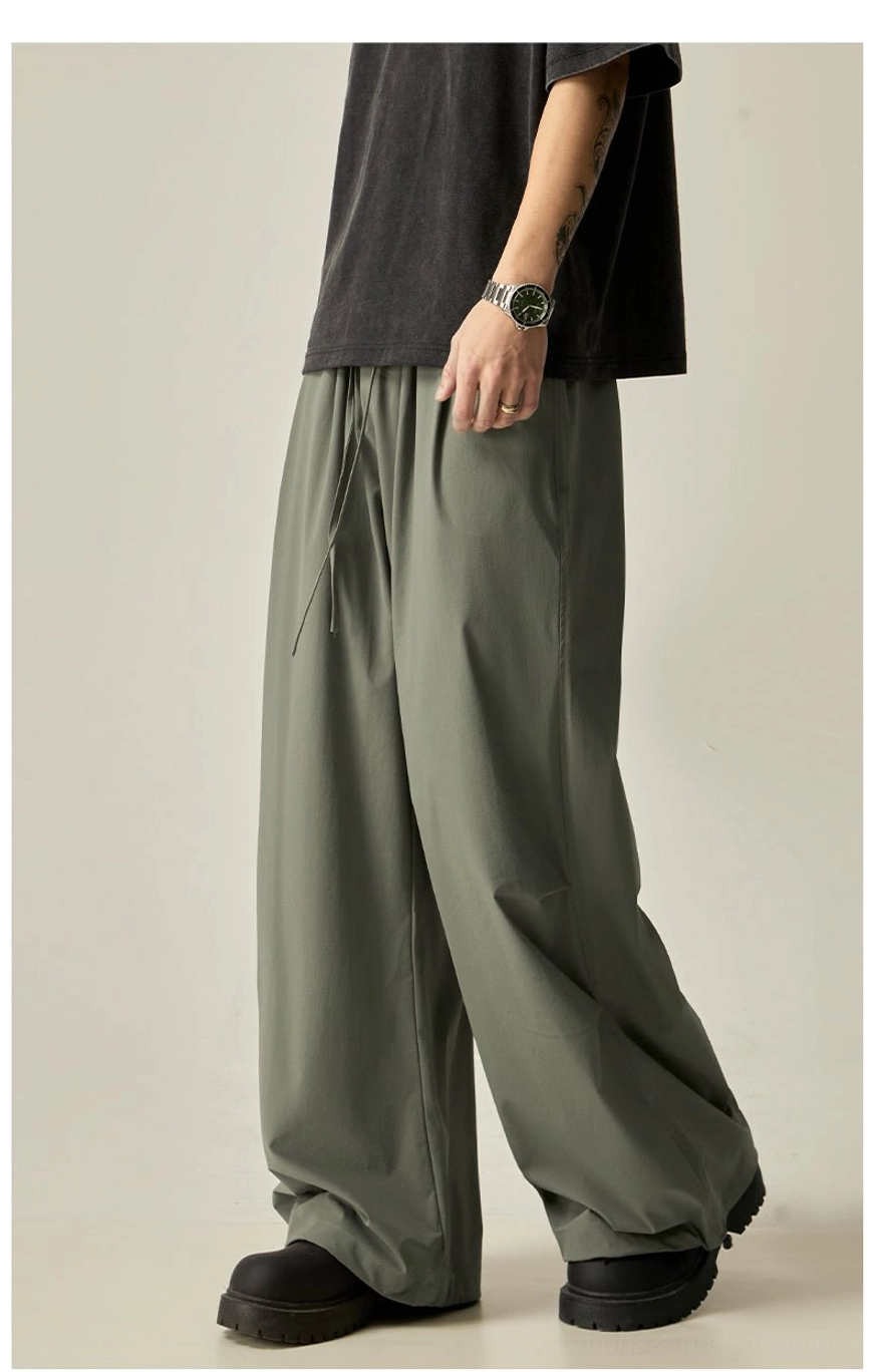 Sage green and black wide leg drawstring pants for men with a relaxed oversized streetwear silhouette
