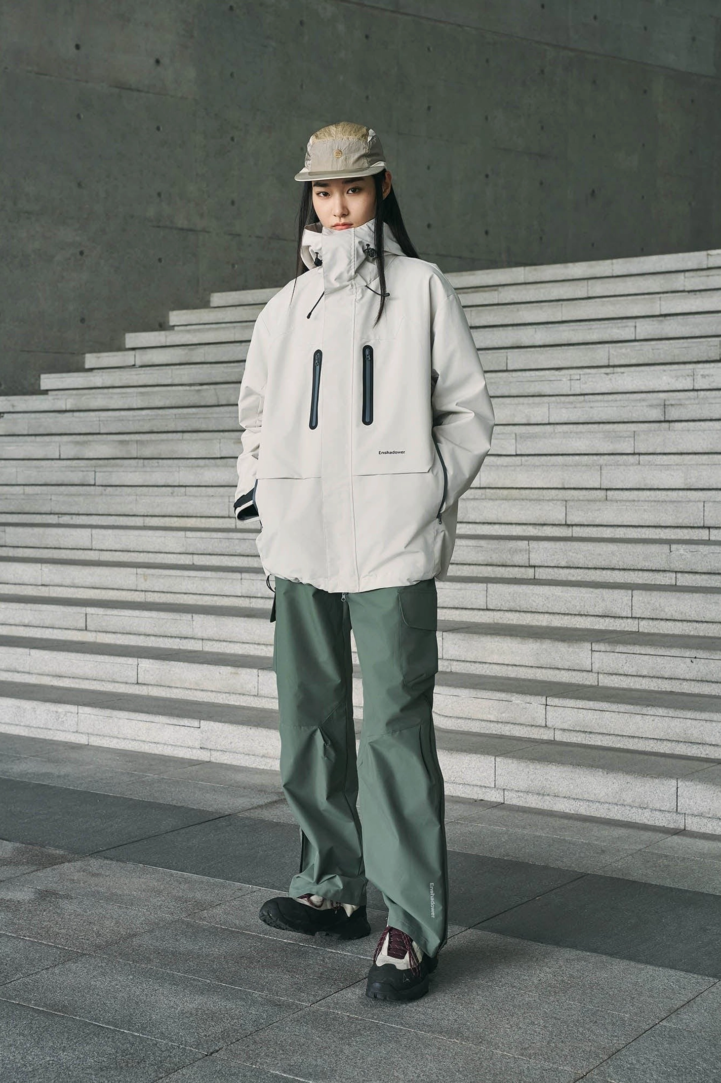Sage green loose straight-leg waterproof cargo pants styled with a high-neck outdoor jacket and bucket hat