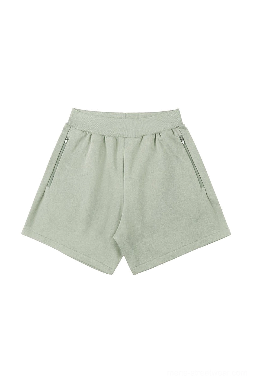 Sage green relaxed unisex sweat shorts with elastic ribbed waistband, secure side zipper pockets, and casual Seoul streetwear silhouette