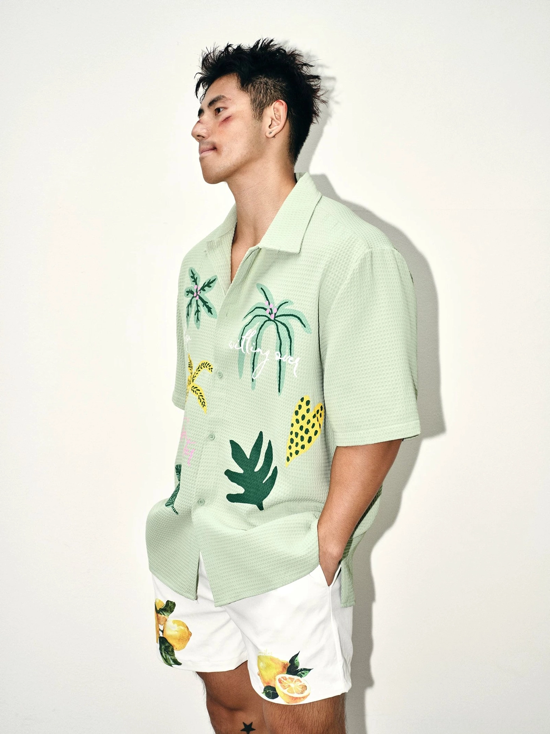 Side view of mens sage green tropical camp collar shirt in textured waffle fabric with embroidered botanical front details