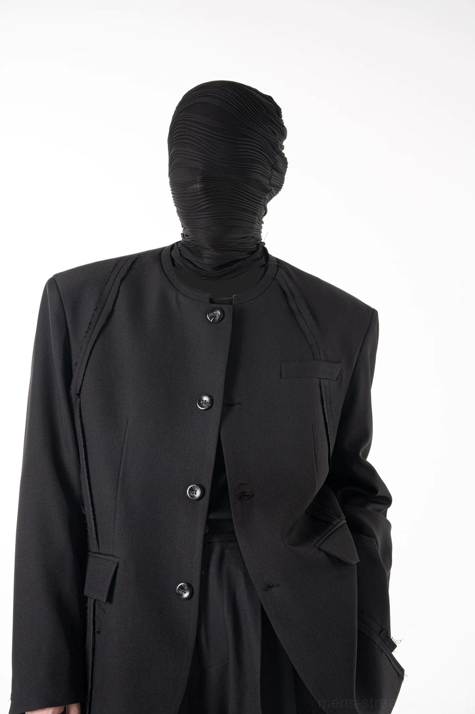 Front detail of sculpted black blazer and matching trousers showing structured shoulders layered seams and multiple buttons