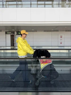 Back view of yellow structured full-zip hoodie on a model walking through an airport with luggage