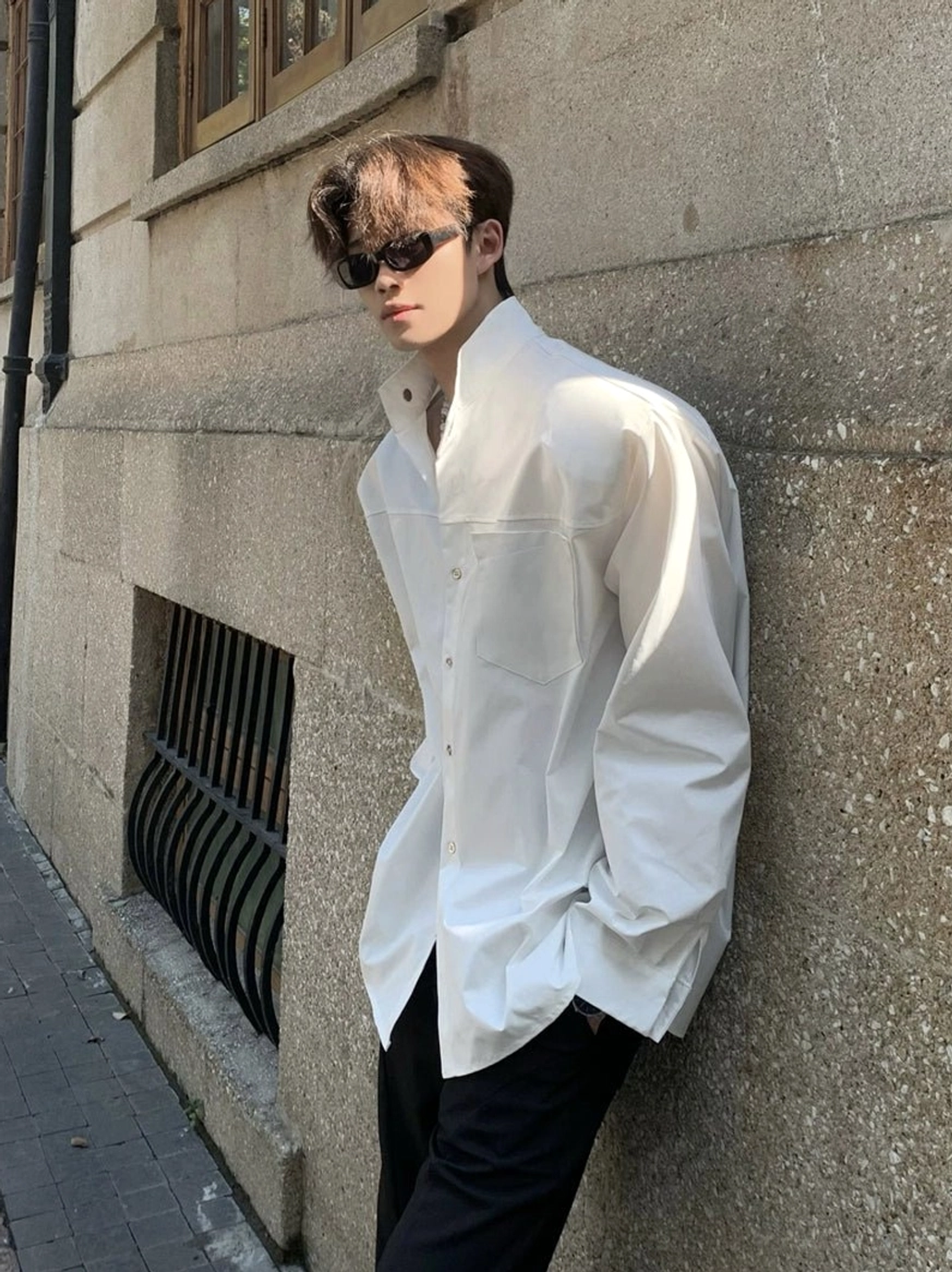 White sculpted collar oversized button up shirt leaning street style view with relaxed long sleeve fit
