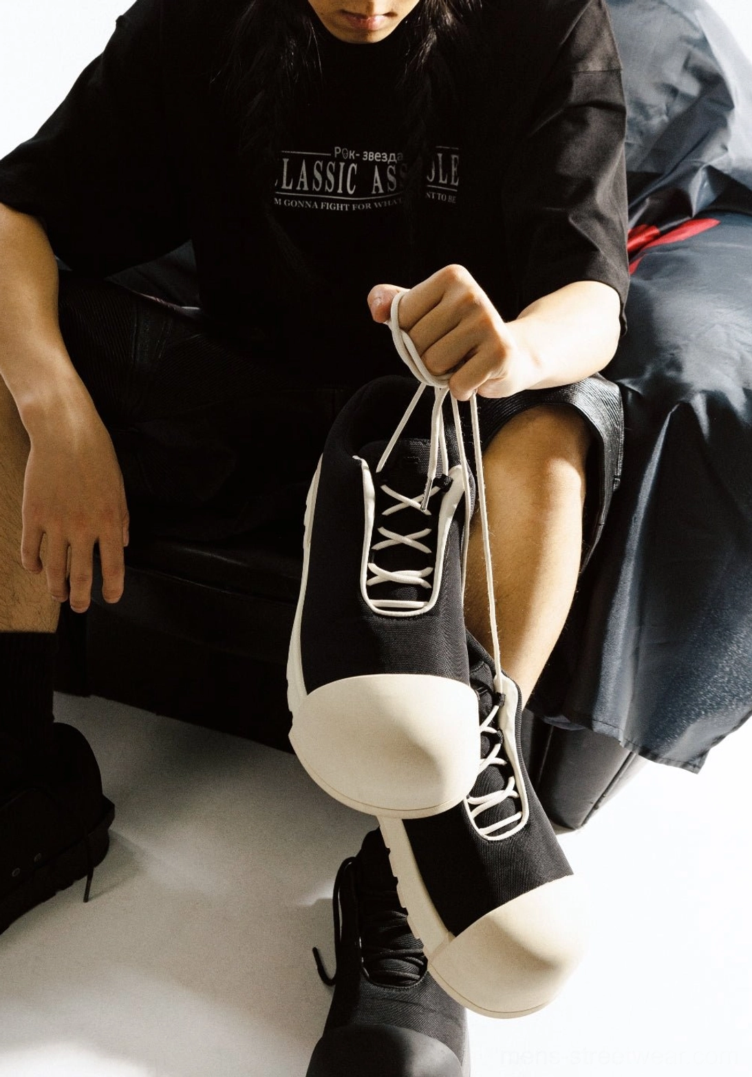 Handheld view of black lace-up platform low boot highlighting the rounded contrast toe and thick sole structure