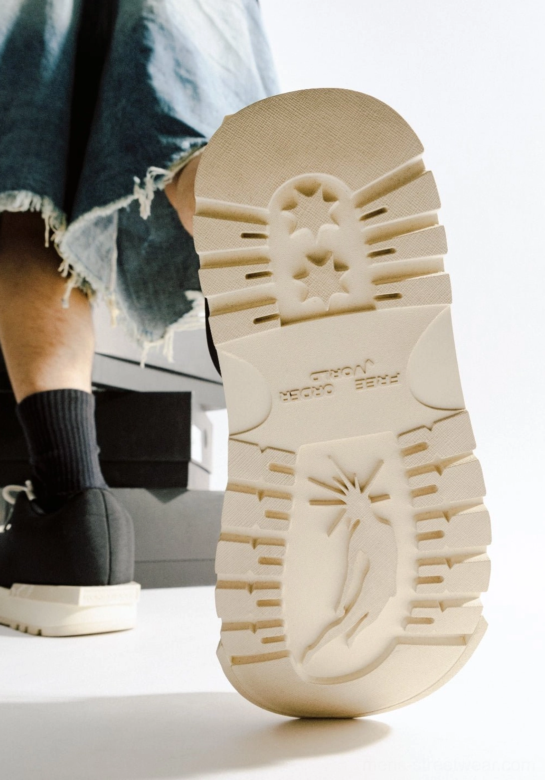 Rear close-up of the off-white heavy tread outsole on black sculpted-toe platform low boots