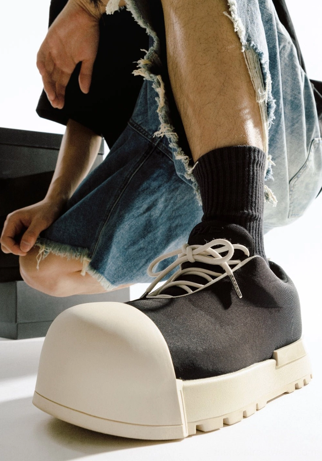 Single black low platform boot with oversized pale rounded toe and chunky two-tone streetwear sole