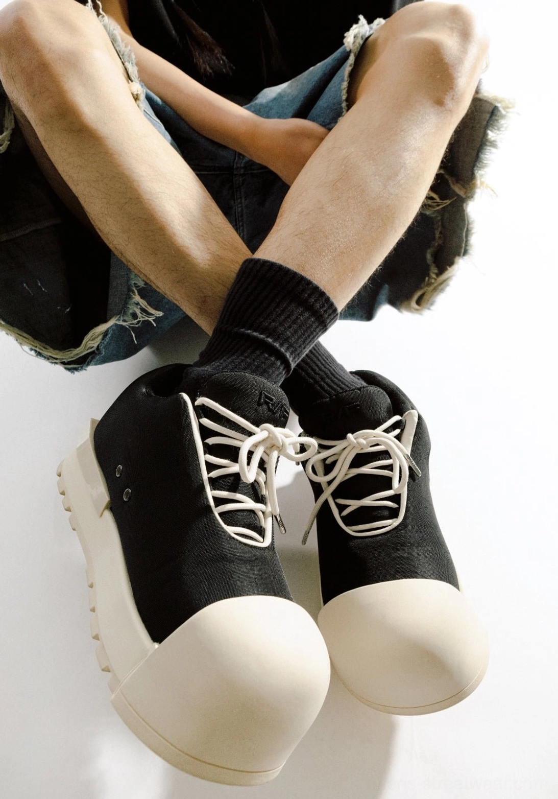 Top-down view of matching black and off-white sculpted-toe platform boots styled with casual streetwear