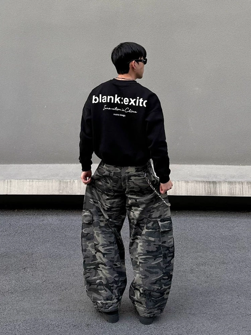 Right rear view of Korean streetwear model wearing oversized grey camo cargo balloon pants with stacked hem, cargo pockets, and waist chain