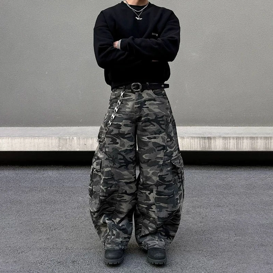 Full body front view of oversized dark grey camouflage balloon pants with multiple cargo pockets, wide legs, black sweatshirt, and chain detail