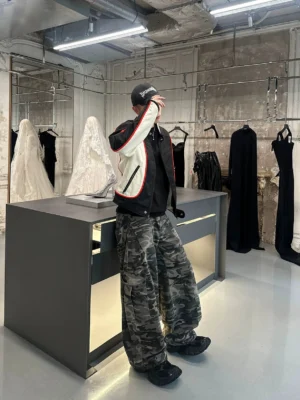 Back three-quarter view of grey camouflage loose-fit cargo pants with wide legs and dimensional side utility pockets in a boutique setting