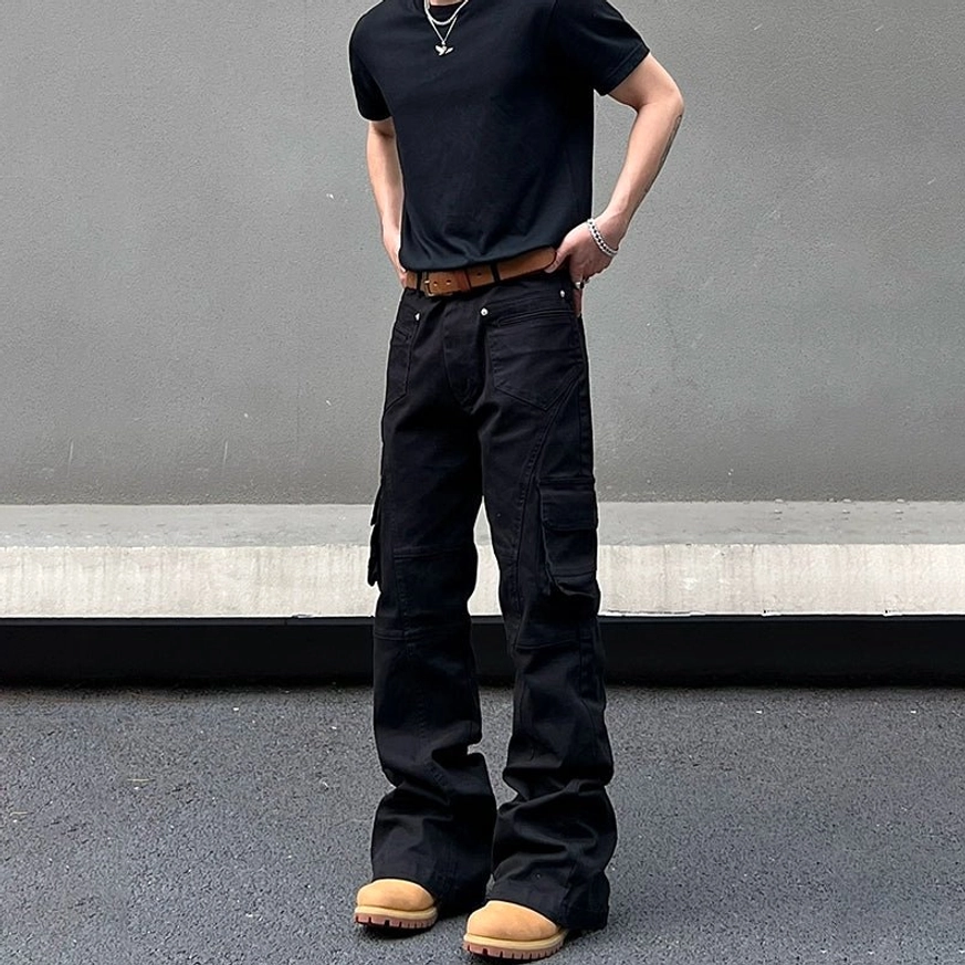 Black flared cargo pants with front button closure and classic utility pockets paired with a plain black tee and tan work boots