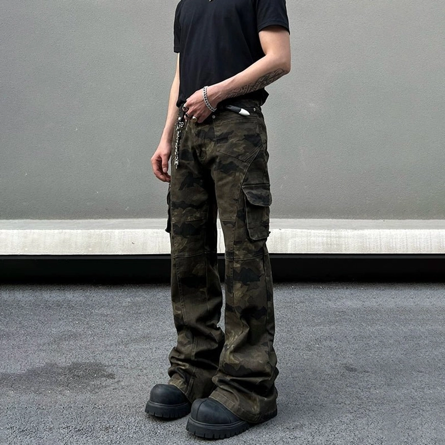 Rear side view of olive camouflage flared cargo pants with multiple pockets, wide stacked legs, black T-shirt, and work boots
