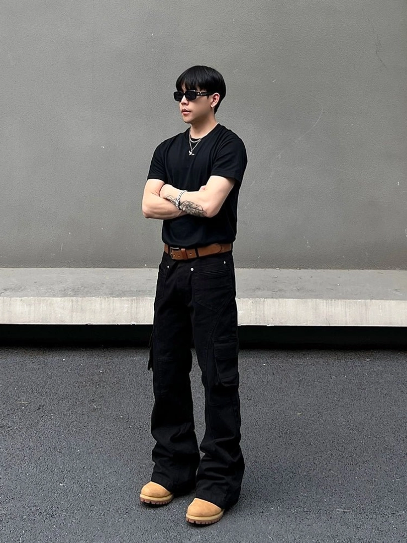 Front full-body view of structured black cargo pants with fitted waist and flared legs styled with sunglasses and silver necklace