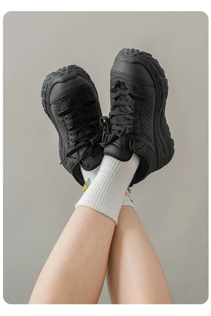 First-person view of all-black chunky utility trainers with perforated panels, rugged traction outsole, and printed white socks