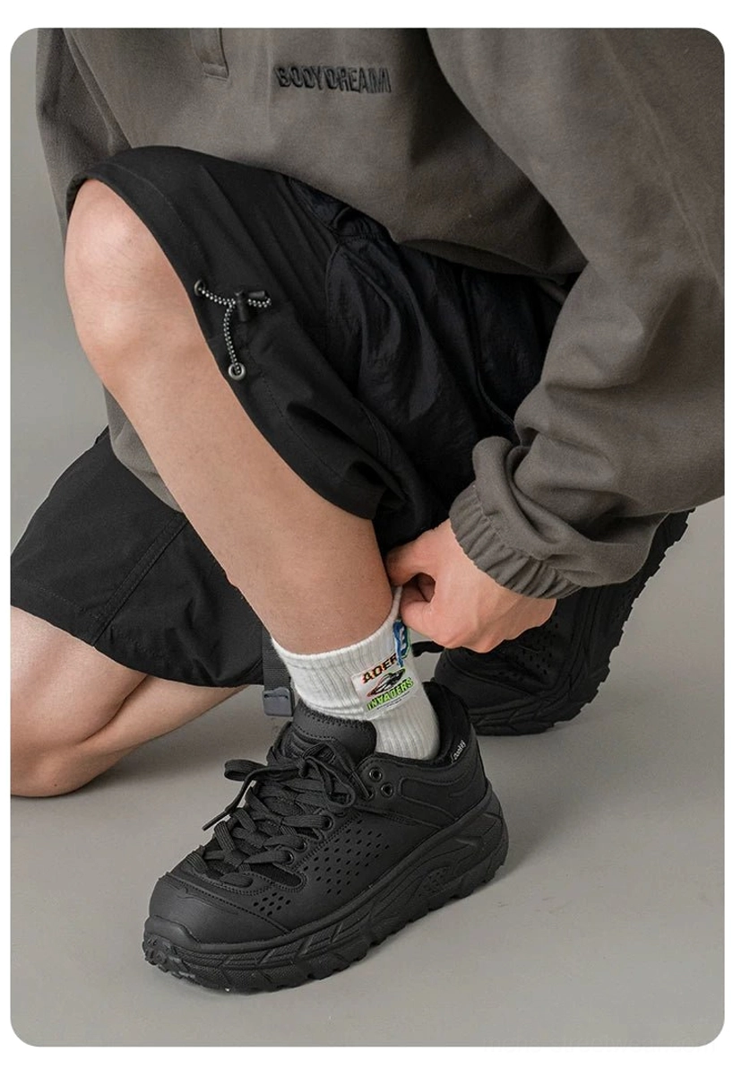 Low-angle side view of black low-top workwear sneakers with a streamlined chunky sole styled with contemporary streetwear