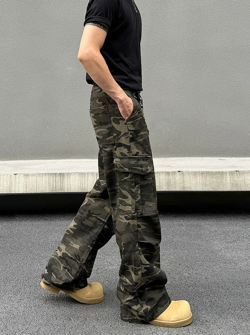 Side walking view of fleece lined woodland camo wide-leg cargo pants with oversized flap pocket and tan boots