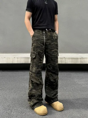 Front full-body view of shadow woodland camo wide-leg streetwear cargo pants styled with a black shirt and tan work boots