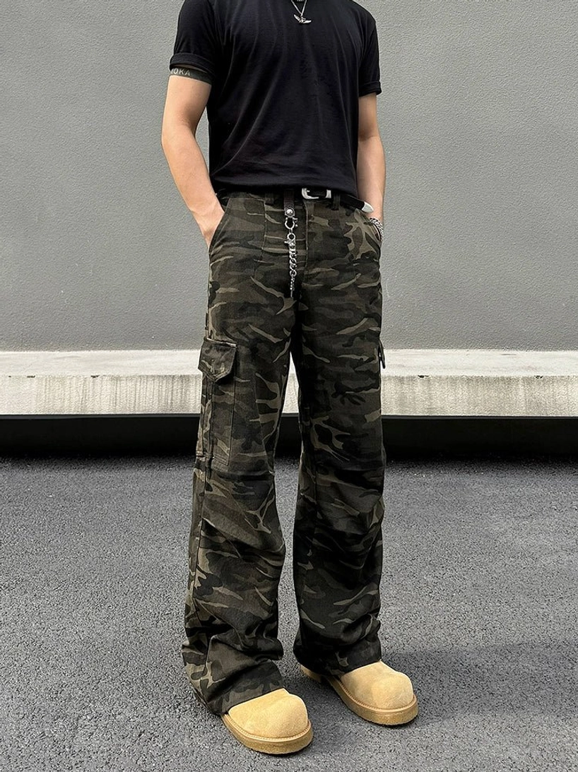 Front full-body view of shadow woodland camo wide-leg streetwear cargo pants styled with a black shirt and tan work boots