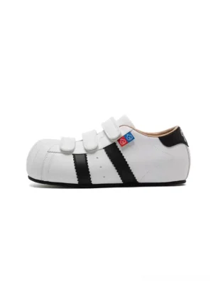 White and black shell-toe velcro strap sneakers with hidden 3cm lift shown from the left front on a white background