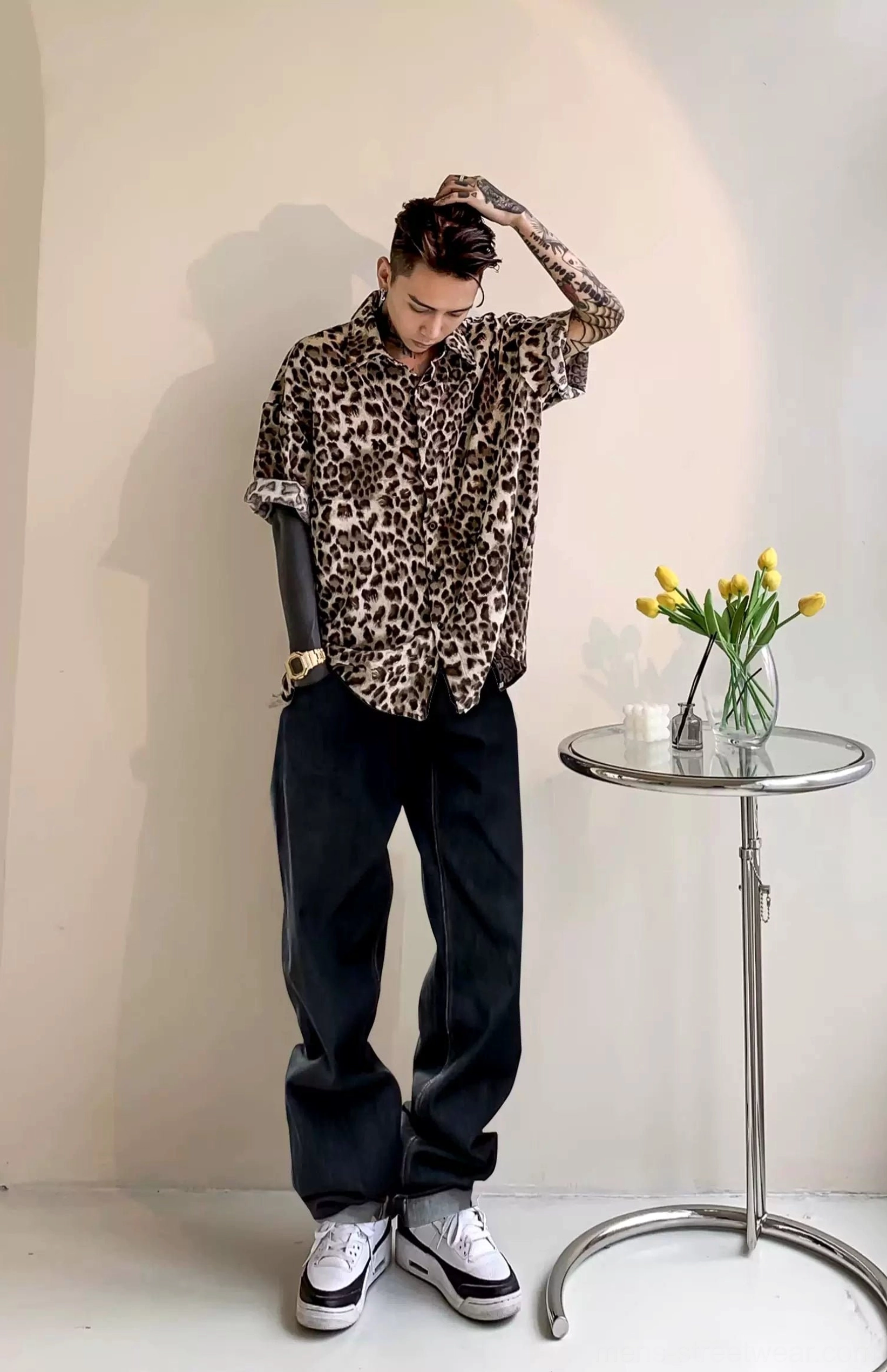 Side view of a relaxed leopard print satin shirt with short sleeves styled with wide-leg dark denim and casual sneakers