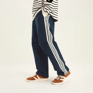 Navy blue side striped athletic pants with a relaxed straight-leg silhouette and contrasting white stripes in a streetwear outfit