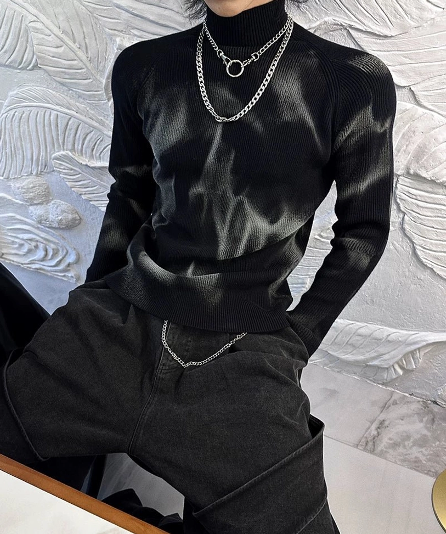 Side view of slim fit black ribbed turtleneck sweater with gradient grey tie-dye details paired with wide-leg denim and chain belt
