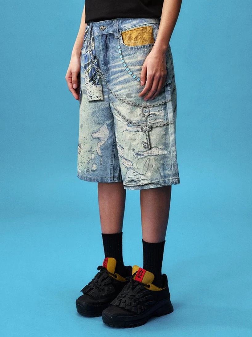 Side front view of relaxed plaid chain denim jorts with decorative chains, leather-look pocket flap and faded blue finish