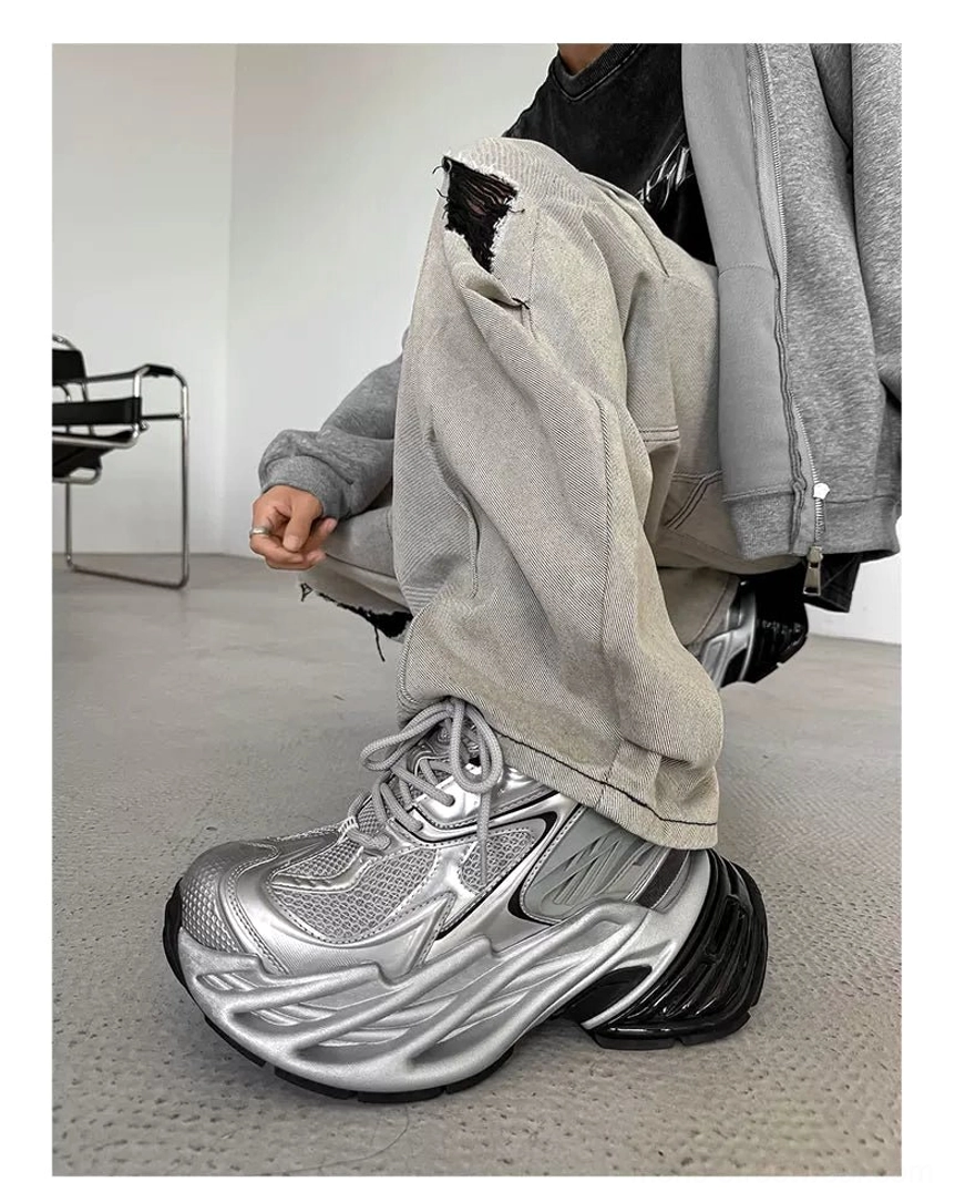 Silver and black chunky platform sneaker with oversized sculpted sole styled with ripped wide-leg jeans