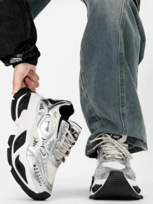 Rear side view of futuristic silver and black chunky platform sneakers with layered synthetic panels, padded collar and sculpted wave outsole